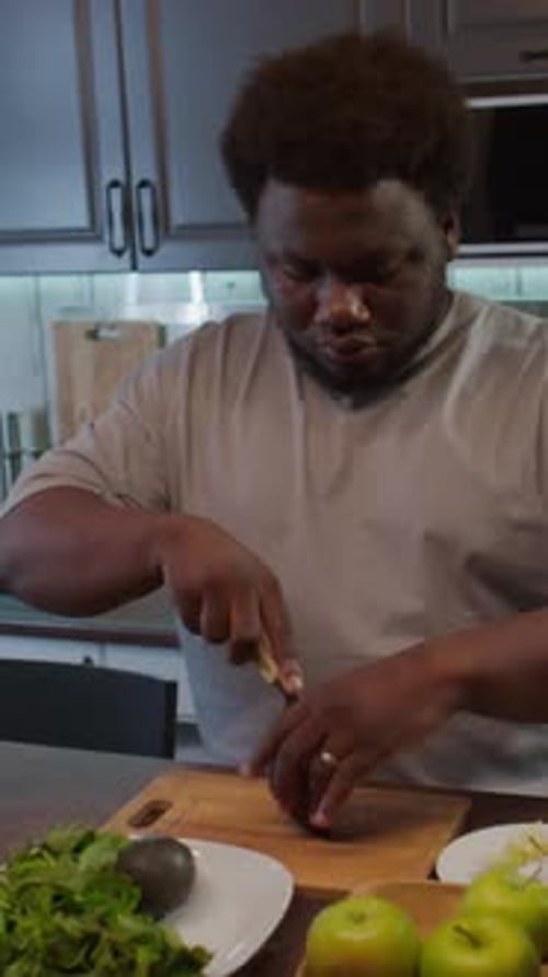 Man Cuts Fresh Avocado in Modern Kitchen