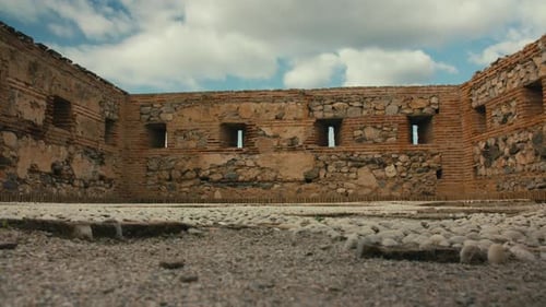 Low-angle view of historic fortress interior with stone walls and sky visible through narrow opening