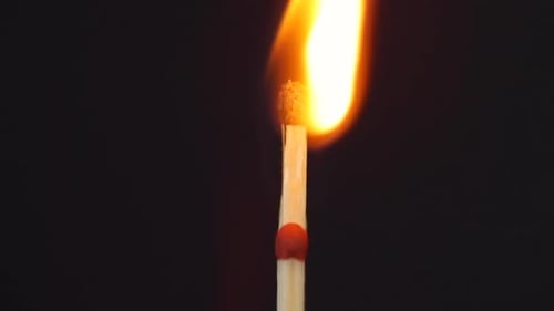 Slow ignition of ignition of two matches close up macro shot captured from the left side on the blac