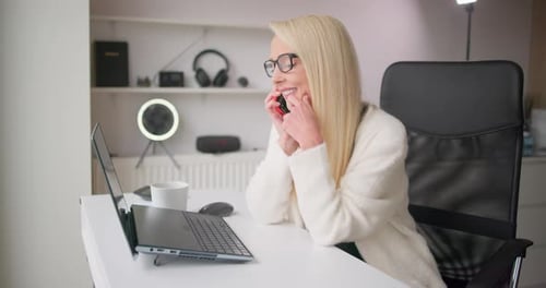 Young Beautiful White Blonde Woman in Casual Clothes Works Typing on Laptop Keyboard and Pauses to