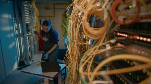 Technician Fixing Cables in Dimly Lit Server Room
