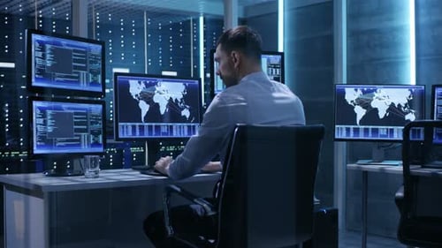 Controlador técnico trabajando en su estación de trabajo con varias pantallas. Está solo en el control del sistema