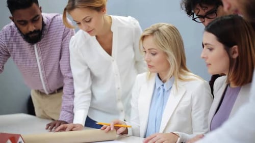 Multiethnic business team discussing house project blueprint at modern office