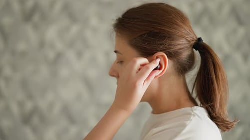 Woman Puts Wireless Earbud In Ear