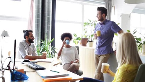 Happy multiethnic business team drinking coffee and discussing ideas in office