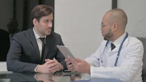 Doctor Showing Patient Digital Tablet in Office