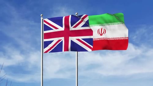 United Kingdom and Iran National Flags Waving Against Blue Sky