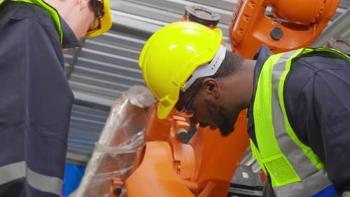 Zwei junge Ingenieure treffen sich und erklären etwas über Roboterarmtechnologie.