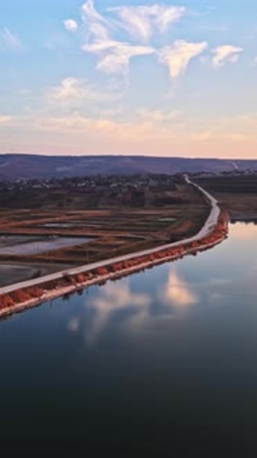 Vue aérienne par drone d'un lac entouré de champs en Moldavie au coucher du soleil. Verticale