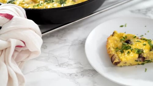 Slicing Freshly Baked Spinach and Ham Frittata in Cast Iron Skillet