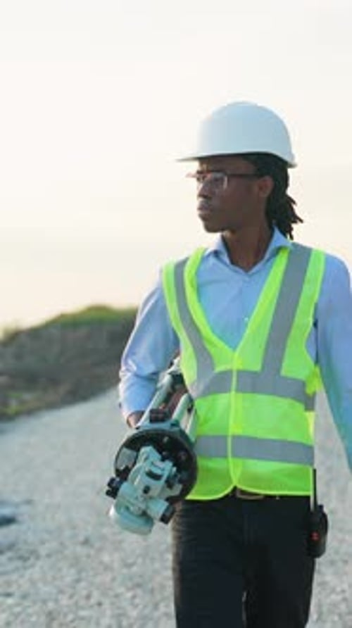 African American Land Surveyor Walking with Theodolite