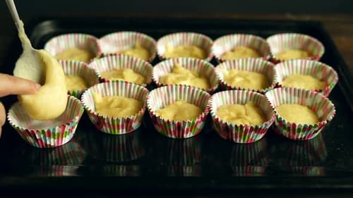 Chef pours sweet vanilla dough into baking tray preparing homemade muffins