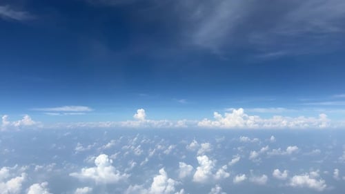 A serene aerial view of drifting clouds and bright sky captured from an airplane window.