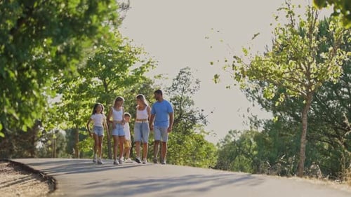 Happy Family Walking in Park Holding Hands