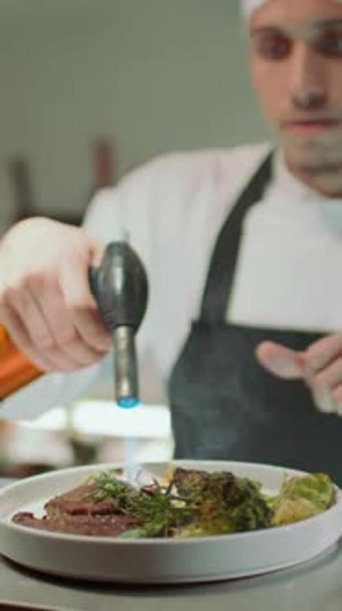 Restaurant Chef Charring Food with Kitchen Torch and Covering Dish