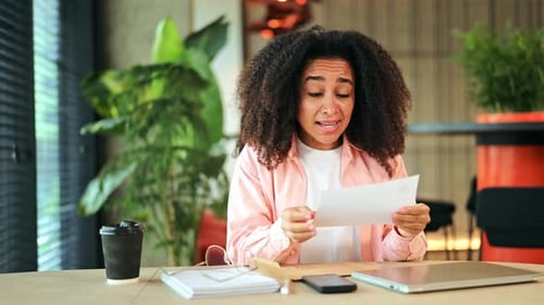 Happy African American Woman Reads Surprising News in Letter Modern Office Desk