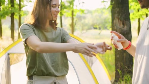 A Group of Young Tourists in a Beautiful Forest Applying Mosquito Repellent at Sunset Against the