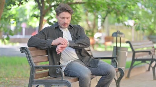 Man Sitting on Park Bench Checking His Watch