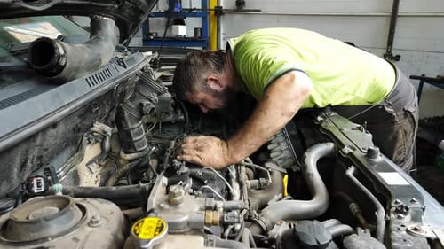 Male Repairer Making Maintenance of Car at Garage Adult Auto Mechanic Working Under Hood of Vehicle