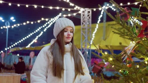 Jovem mulher cheirando árvore de Natal com fundo macio de bokeh
