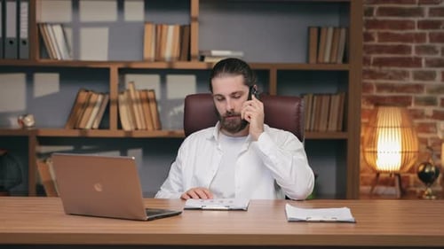 Adult Man Discussing Graphs on Cellphone in Office