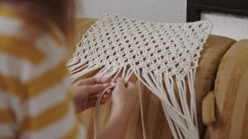 Mujer haciendo macramé en el sofá