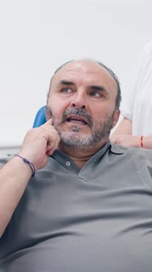 Mature Patient Explaining Dental Problem to Dentist Vertical
