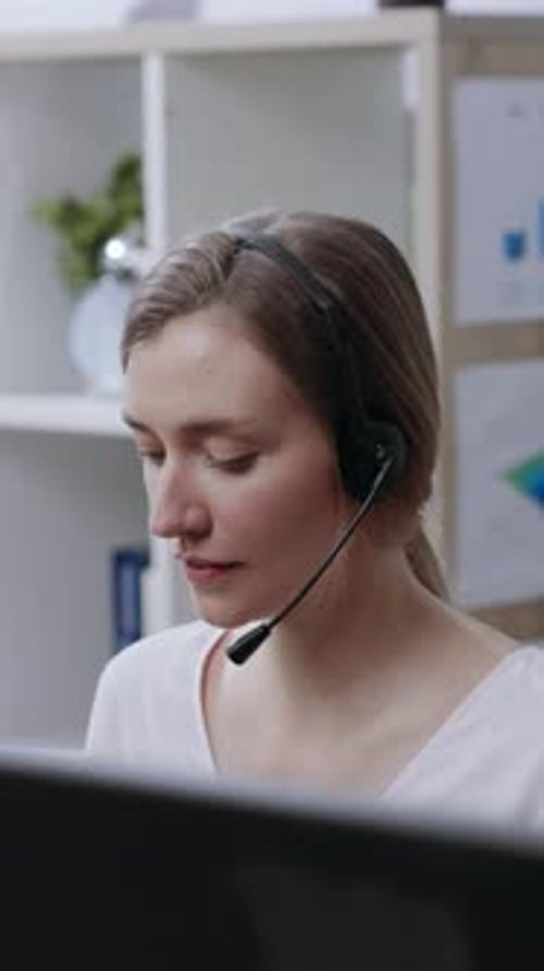 Woman with Headset Smiling at Computer in Office