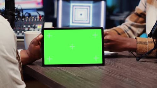 Man Watches Clips on Mockup Tablet Invited to Podcast with Host in Apartment Studio