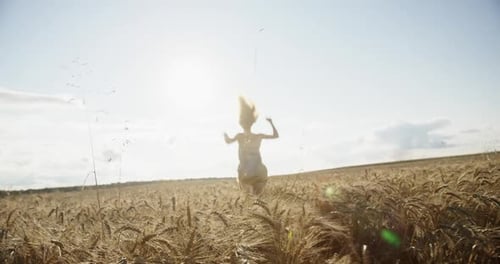 Young Woman Enjoying Freedom in Golden Wheat Field at Sunset