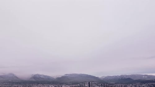 camera tilts down revealing snow-covered mountains and a cityscape.