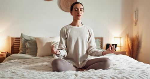 Woman Meditating Peacefully on Bed in Bedroom