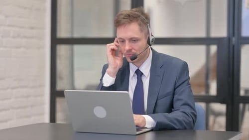 Man Working at Laptop With Headset in Office