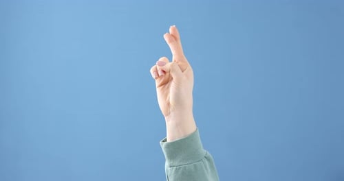 Woman Crossing Fingers Against Blue Background for Luck