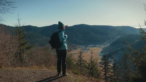 Woman hiker coming to edge of mountain and looking at breathtaking view