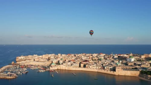 Hot air balloon passing over Acre old city port houses and Mosque at sunrise, Aerial view