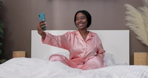 Smiling Woman Taking Selfie in Bed in Pajamas