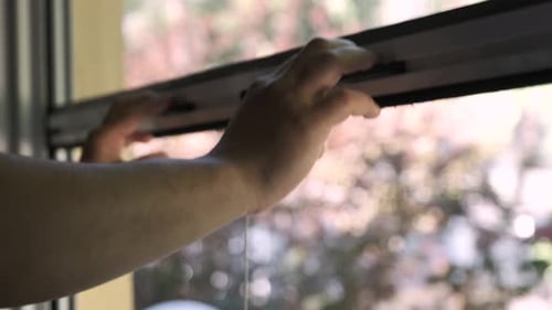 Man hands closing retractable insect screen.