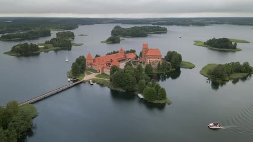 Aerial shot of the Trakai castle surrounded by trees over the Galves lake in Trakai, Lithuania