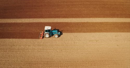 Aerial shot of farming tractor is plowing and cultivating field for future sowing new crops in a s
