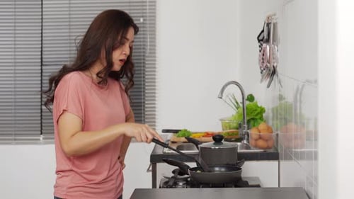 Woman Cooking Food with Frustrated Expression in Kitchen