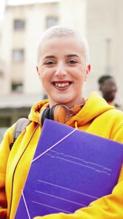 Vertical Portrait of One Young Student Lady with Short Hair Standing at the College Smiling and