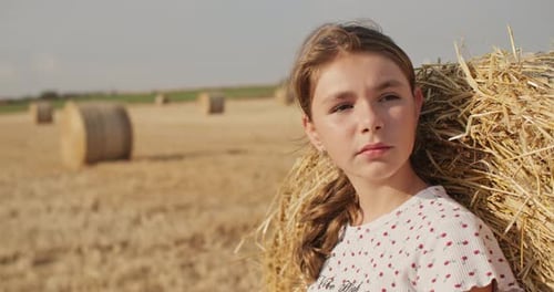 Portrait of a Fairhaired Caucasian Girl in a Field with Hay Bales