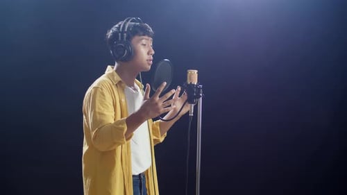 Young Man Singing into Microphone in Studio