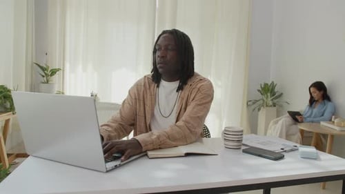 Male Employee Using Laptop while Female Colleague Working on Tablet in Office
