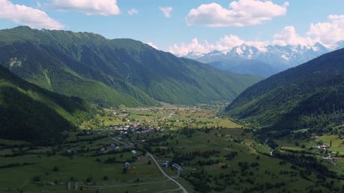 Clouds embracing majestic mountain peak over lush green valley