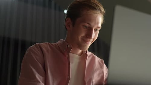 Closeup Lowangle View of Positive Young Man Communicating Online on Laptop Sitting at Comfortable