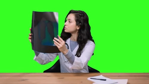 Junge Ärztin in Uniform untersucht Röntgenbild auf dem Chroma-Key