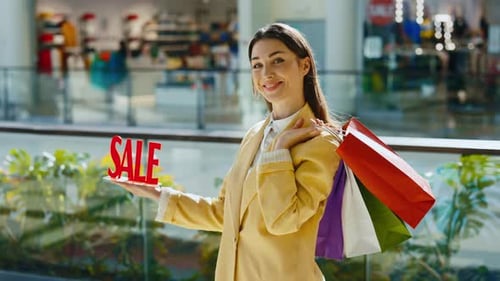 Woman Holding 'Sale' Sign in Shopping Mall