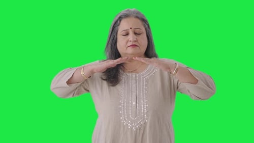 Relaxed Indian old woman doing breathe in breathe out exercise Green screen